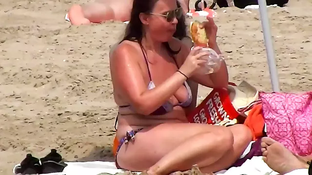 Busty mature lady has a lunch on the beach